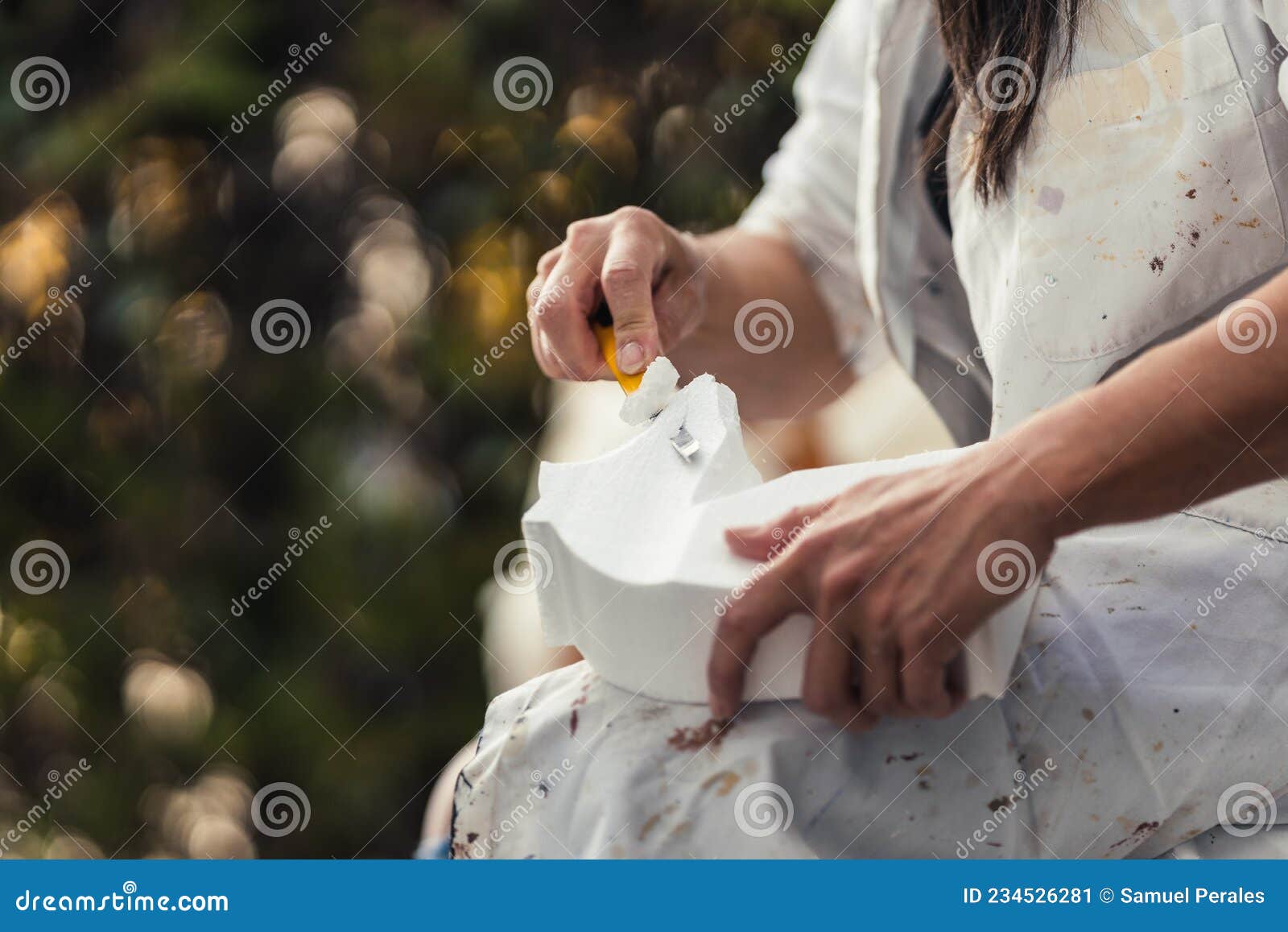 woman cutting part of the surface of a piece of polystyrene outdoors