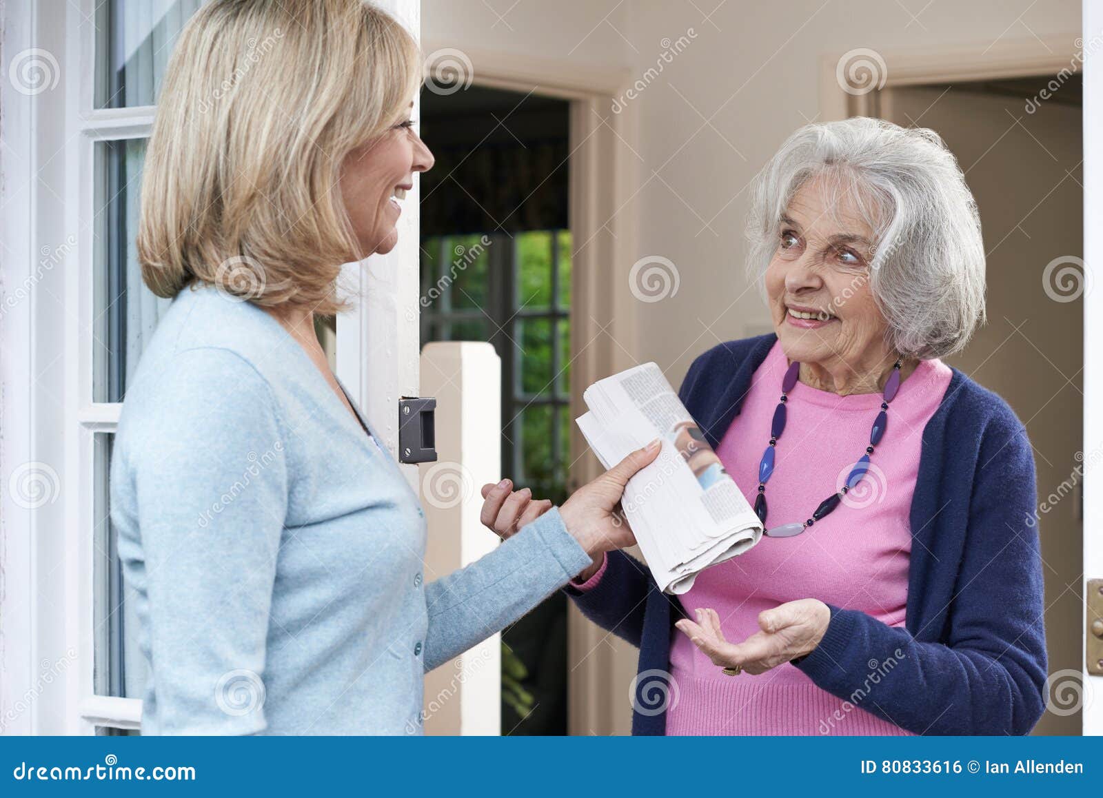 woman delivering newspaper to elderly neighbour