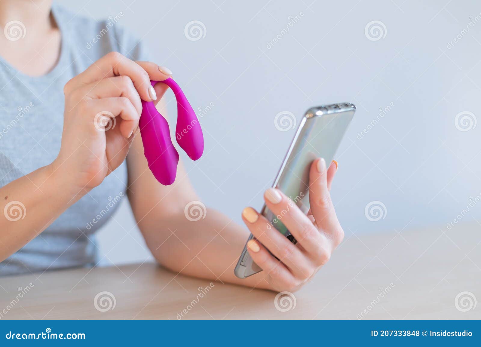A Woman Demonstrates a Modern Curved Clitoral Vaginal Vibrator in Her Video Blog on Her Smartphone photo
