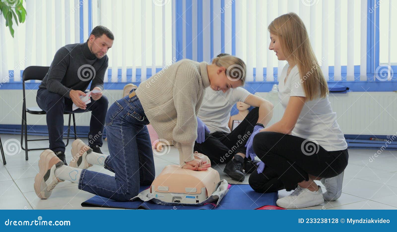 Woman Demonstrating CPR on Mannequin in First Aid Class. Stock Photo