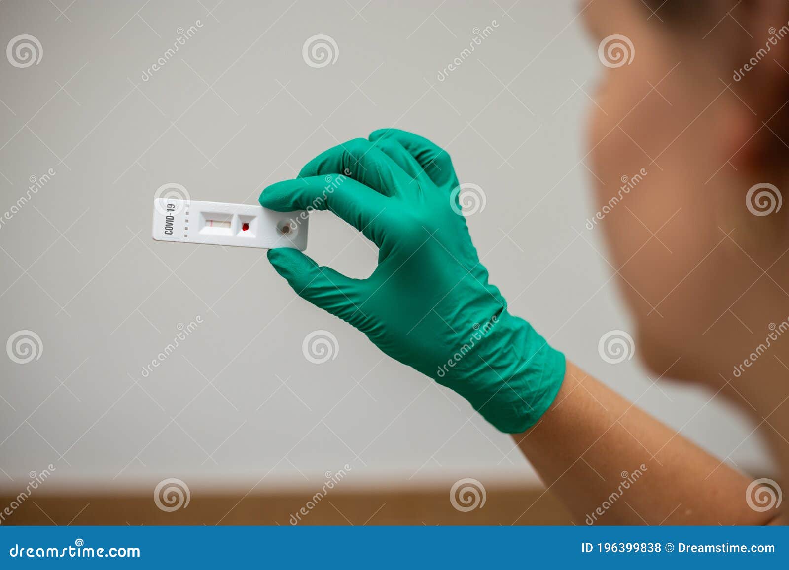 woman doctor looking at covid-19 rapid test wearing green latex gloves