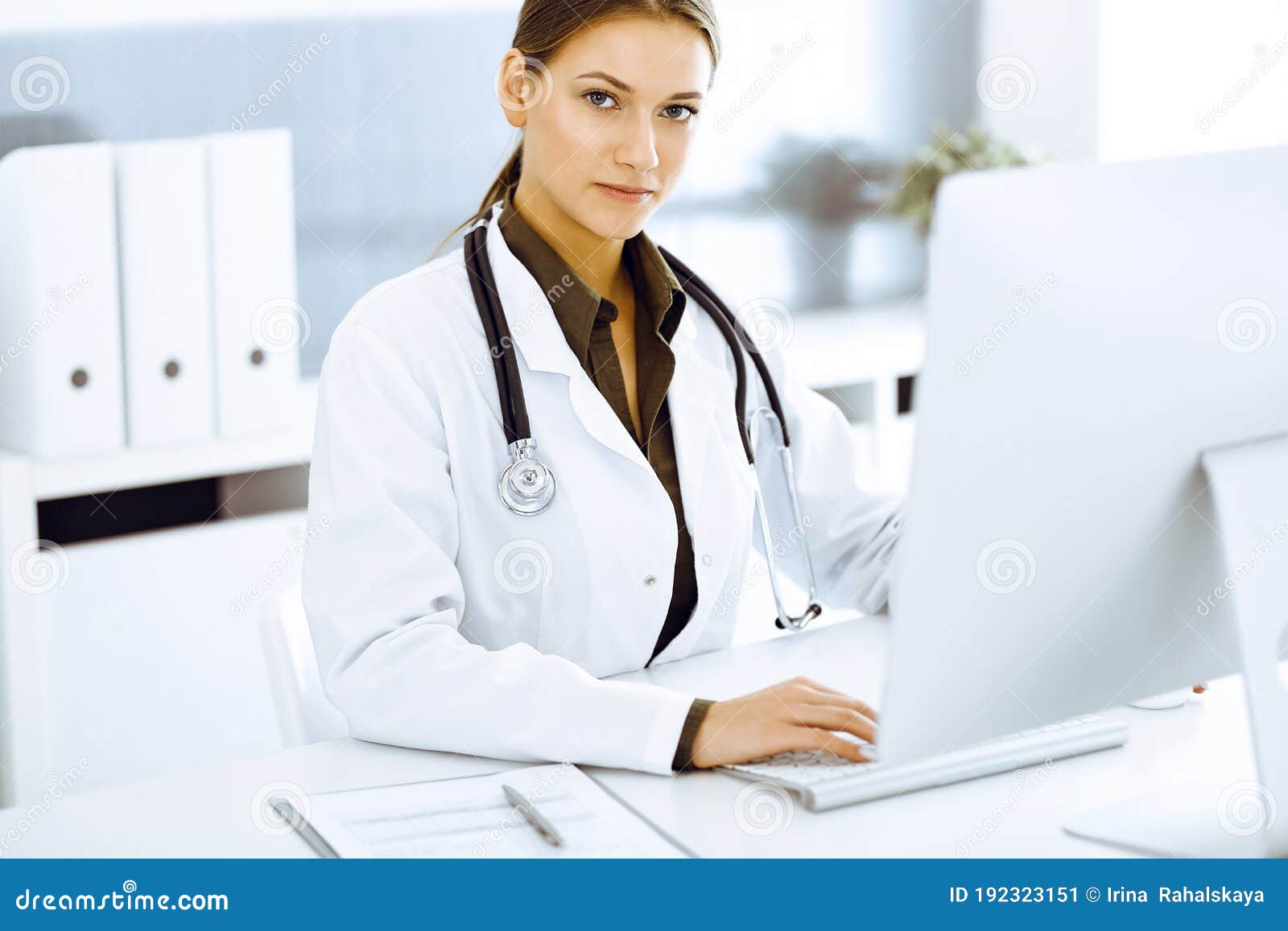 woman-doctor typing on pc computer while sitting at the desk in hospital office. physician at work