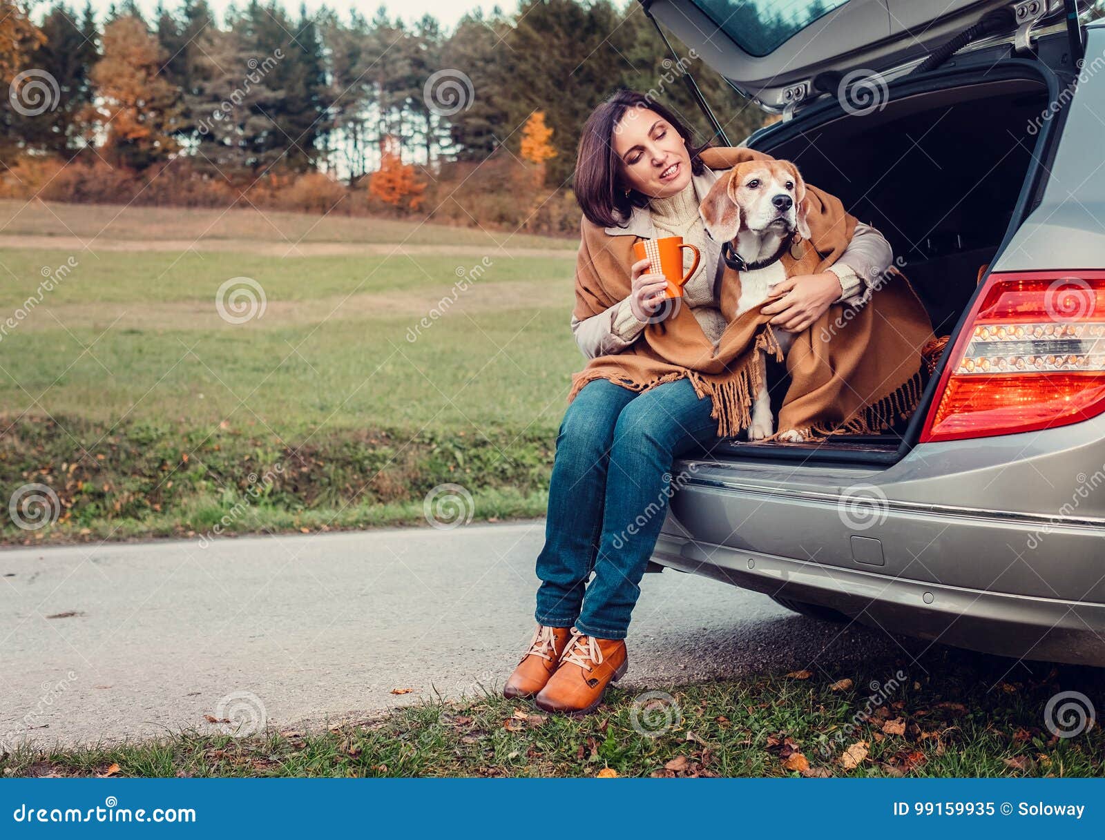 woman with dog sit together in cat truck and warms hot tea