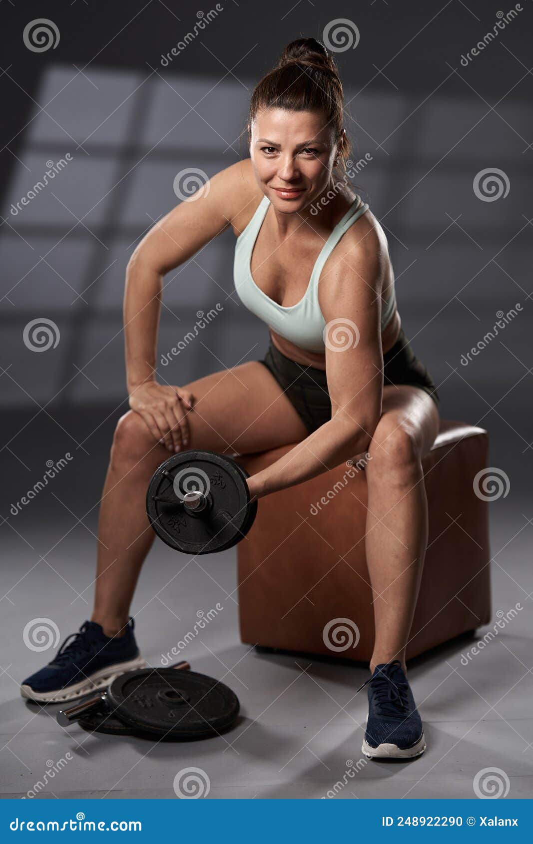 Female bodybuilder doing the seated dumbbell bicep curl Stock Photo by  Iakobchuk