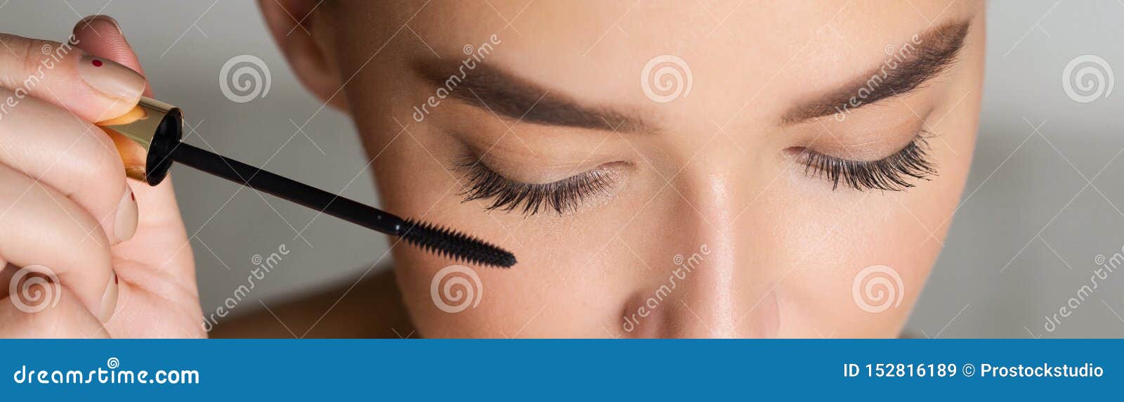 woman doing makeup, applying black mascara, closeup