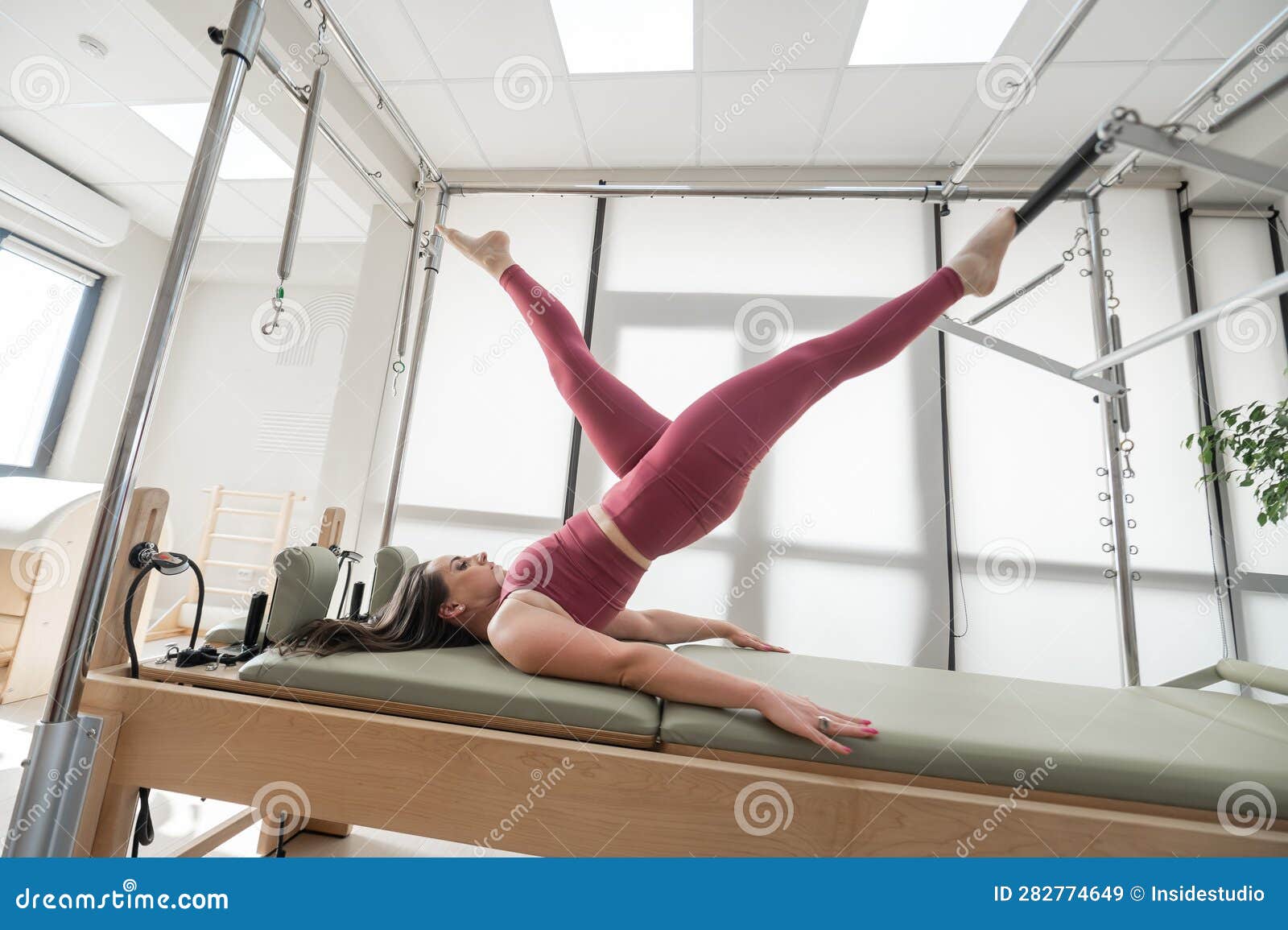 Woman Doing Pilates Exercise on Cadillac Reformer Machine. Stock Image
