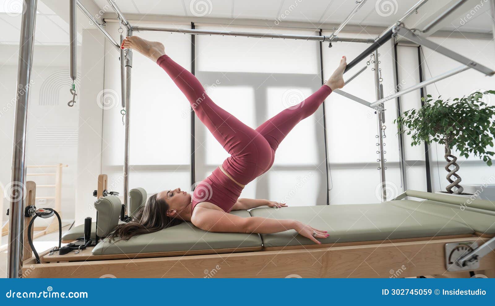 Woman Doing Pilates Exercise on Cadillac Reformer Machine. Stock Image