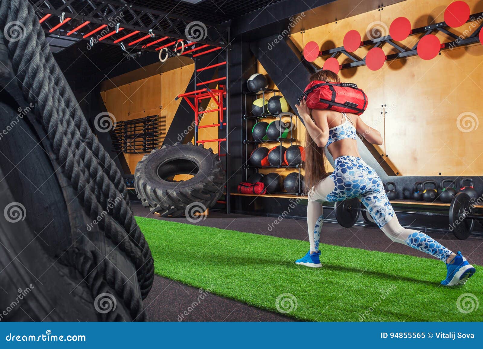 Young beautiful sporty woman doing sit-ups with a sandbag. Woman doing exercises in the gym