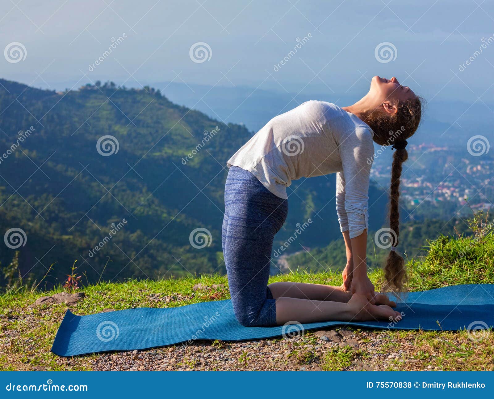 woman doing yoga asana ustrasana camel pose outdoors