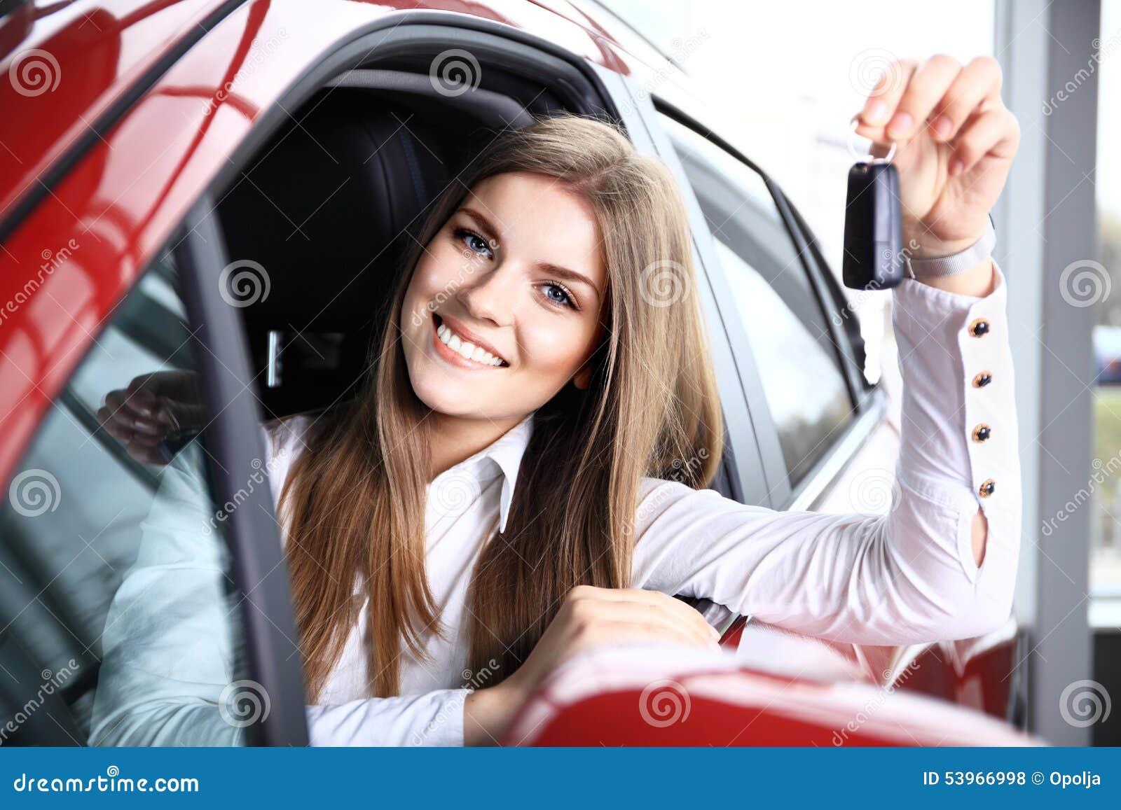 woman driver holding car keys siting in new car