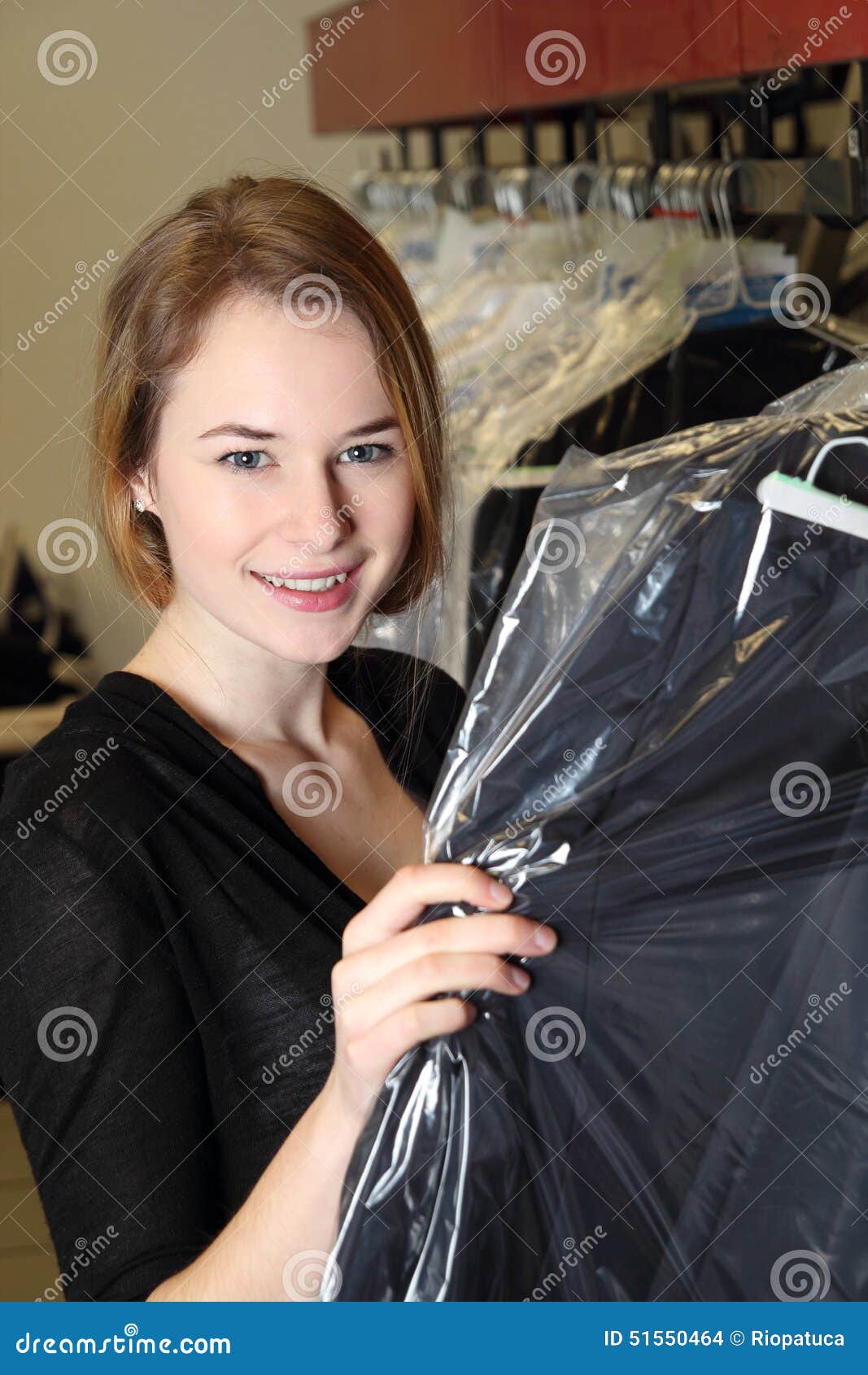 Woman in Dry Cleaning with Clothes Packed in Plastic Foil Stock Photo