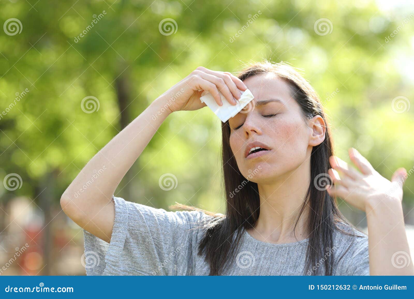 woman drying sweat using a wipe in a warm summer day