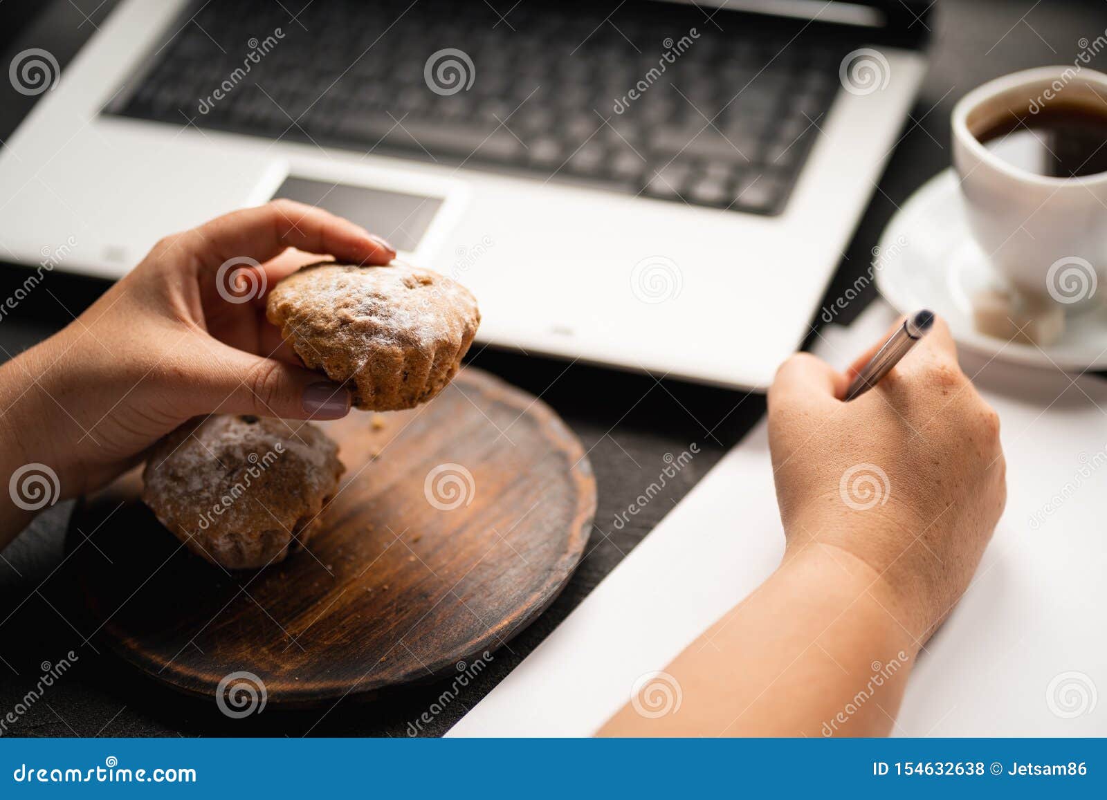 woman eating muffin at workplace. unhealthy snack