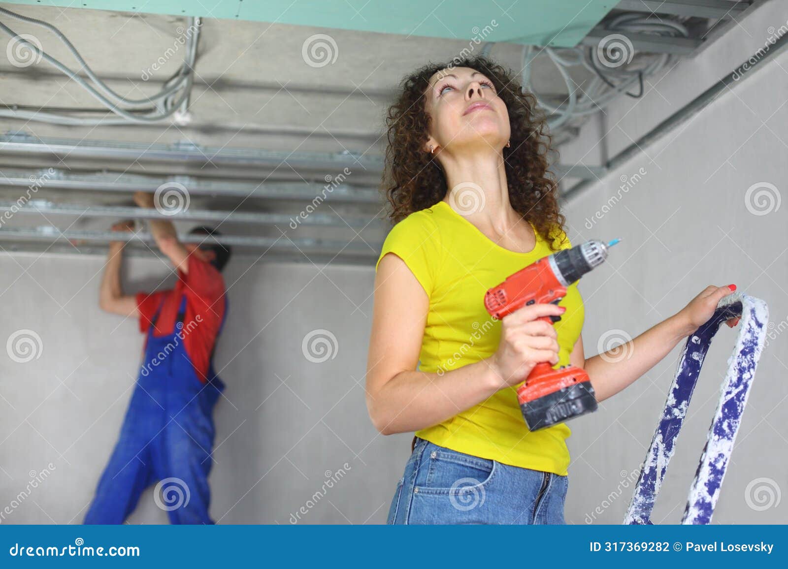 woman with an electric screwdriver and man is