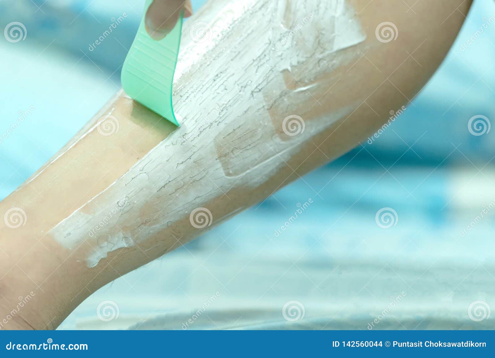 woman epilating leg with depilation cream and spatula