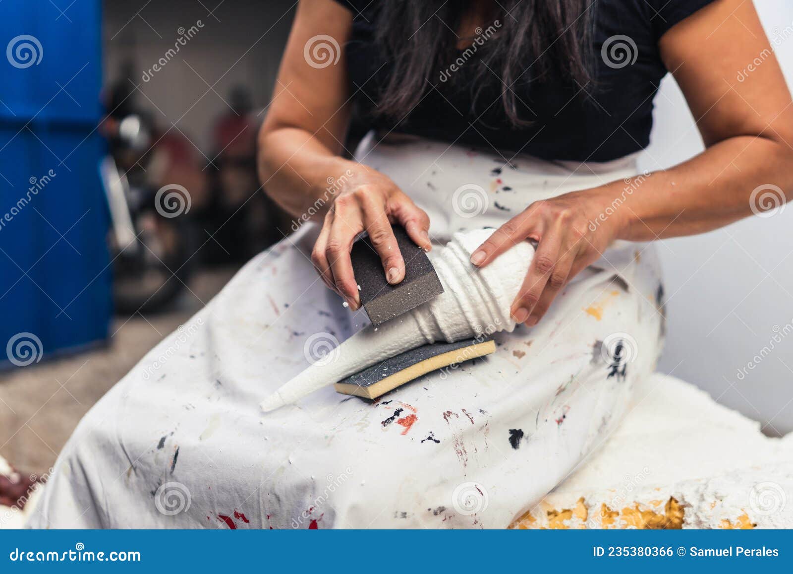 woman filing by hand a polystyrene sculpture in a garden