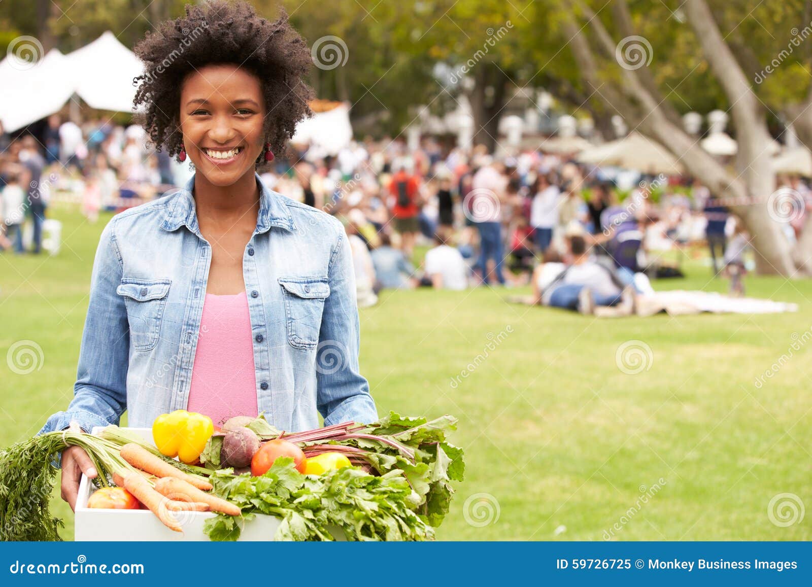 woman with fresh produce bought at outdoor farmers market