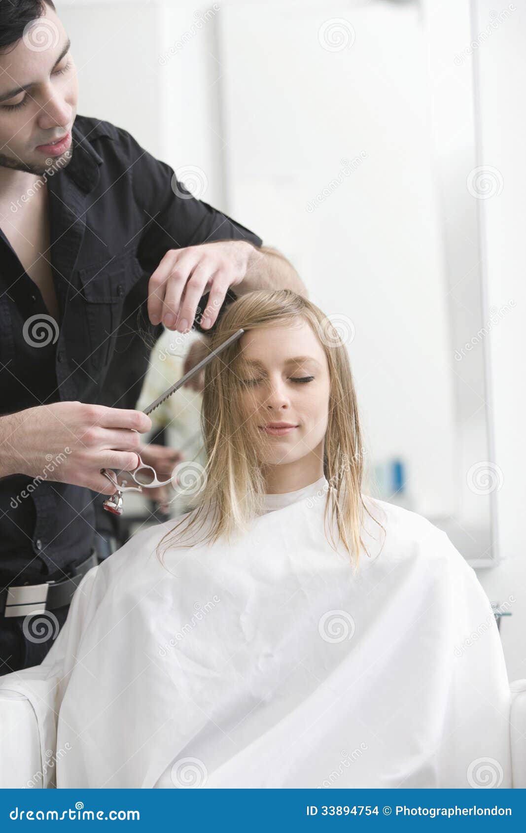 Woman Getting Haircut From Hairdresser At Salon Stock Photo