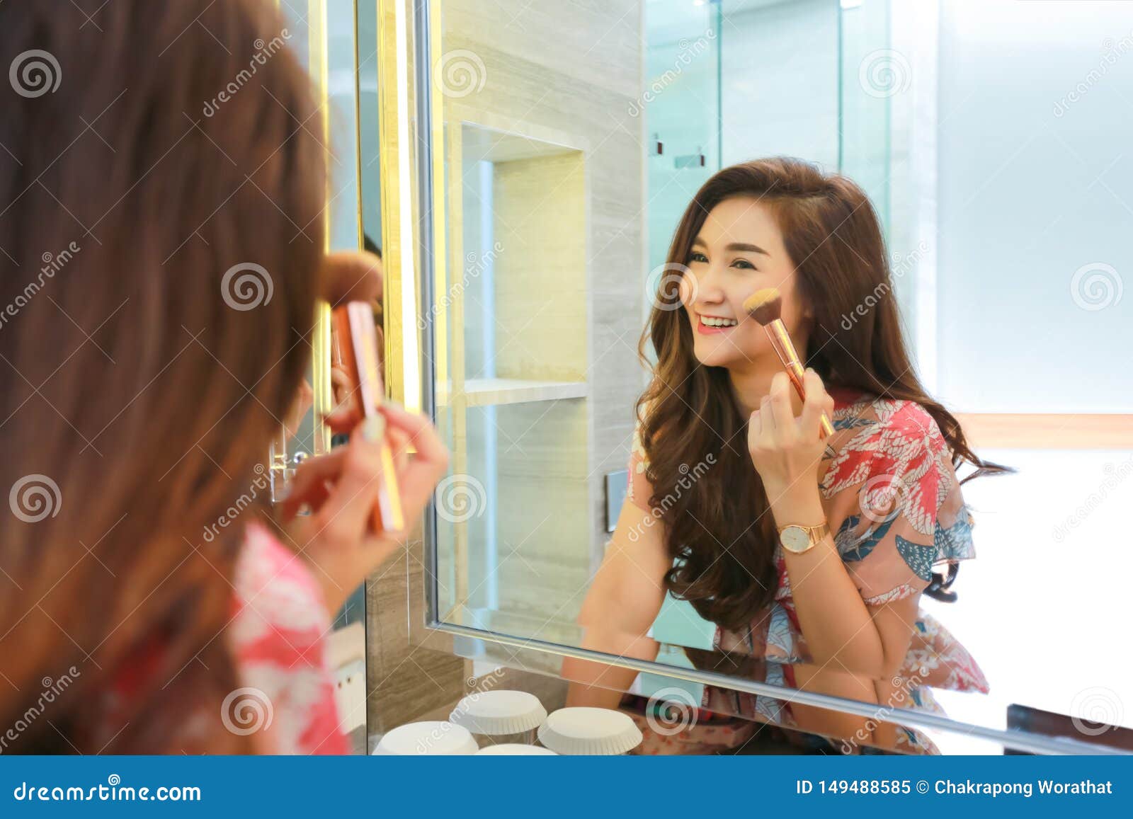 woman getting ready for work makeup routine putting in bathroom mirror at home