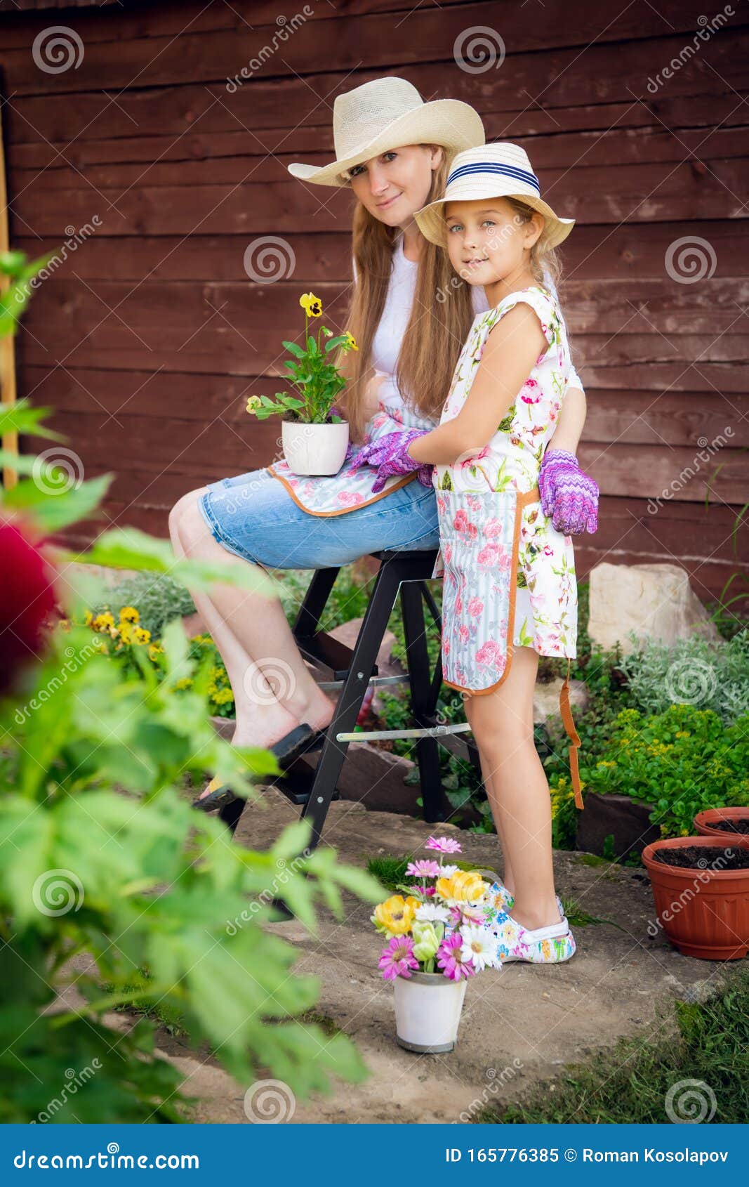 Woman And Girl Mother And Daughter Gardening Together Planting Flowers In The Garden Looking 