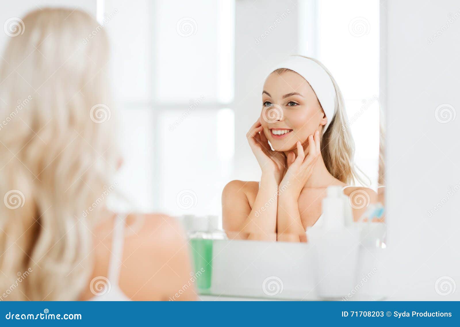 woman in hairband touching her face at bathroom