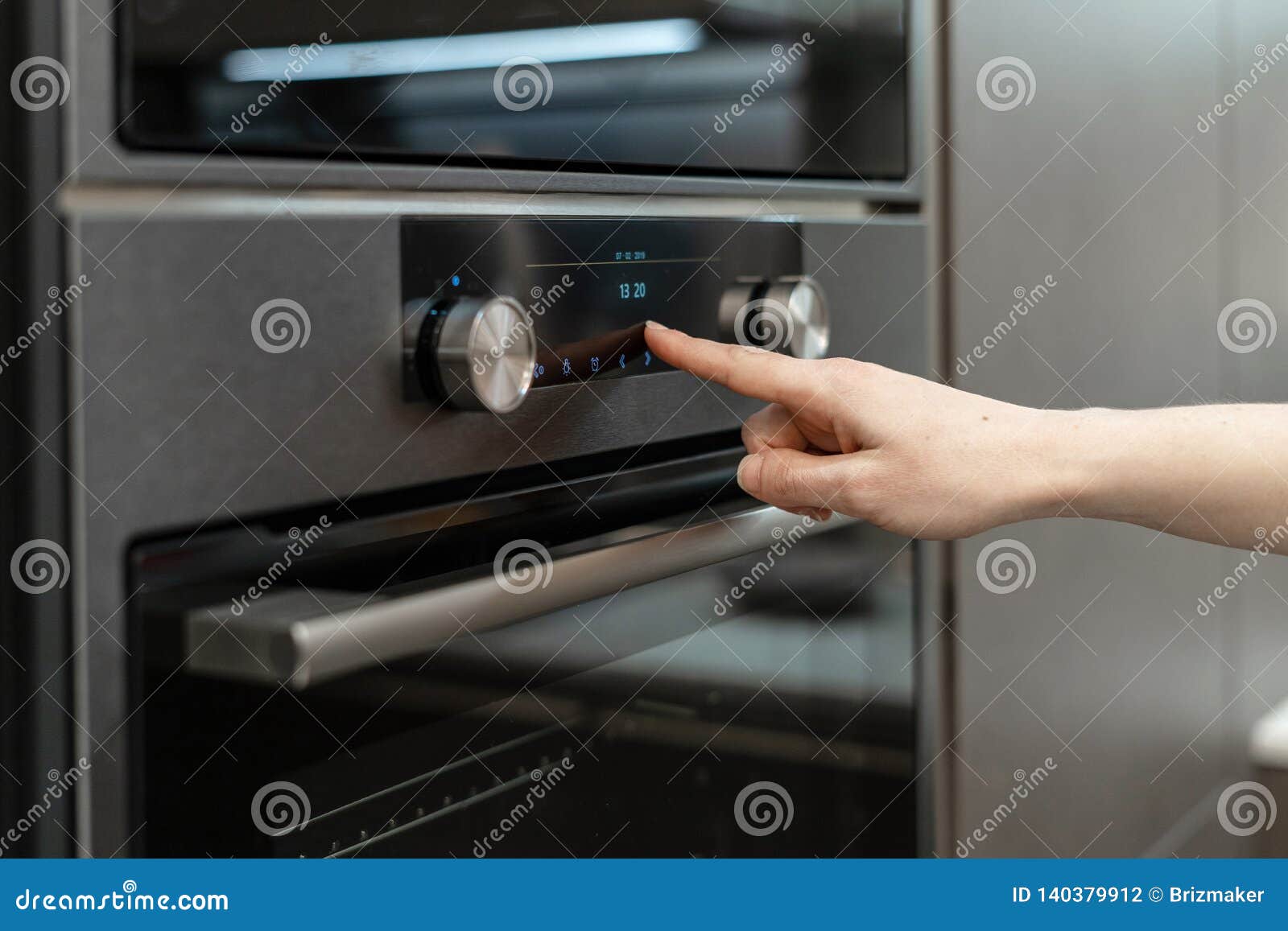 woman hand choose program on electronic control panel built-in oven