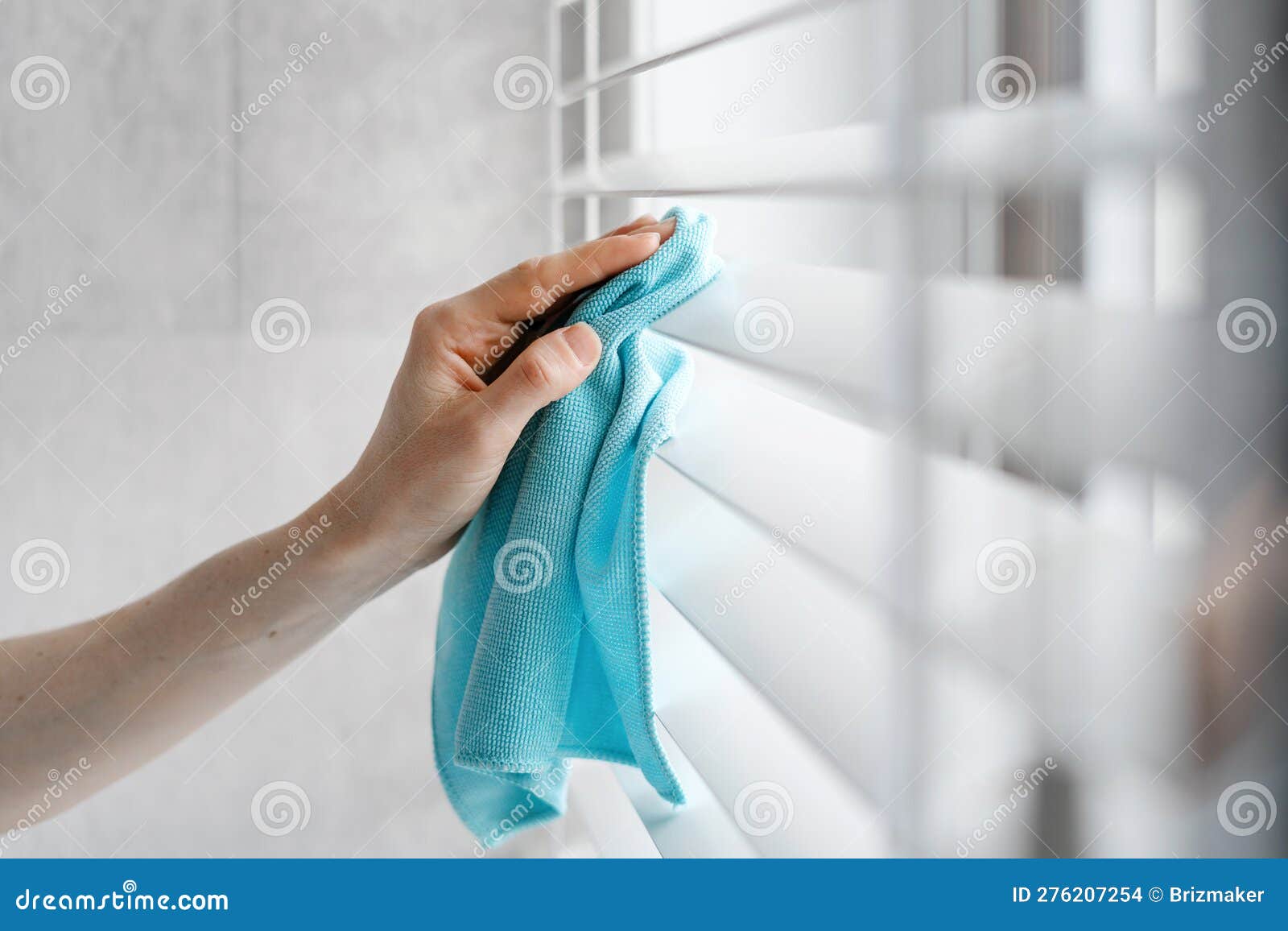 woman hand cleaning window blinds with rag indoors
