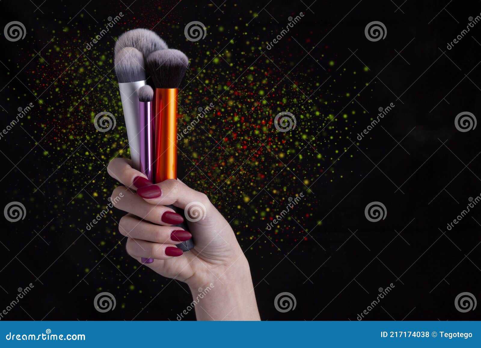 woman hand holding make-up brushes - black background