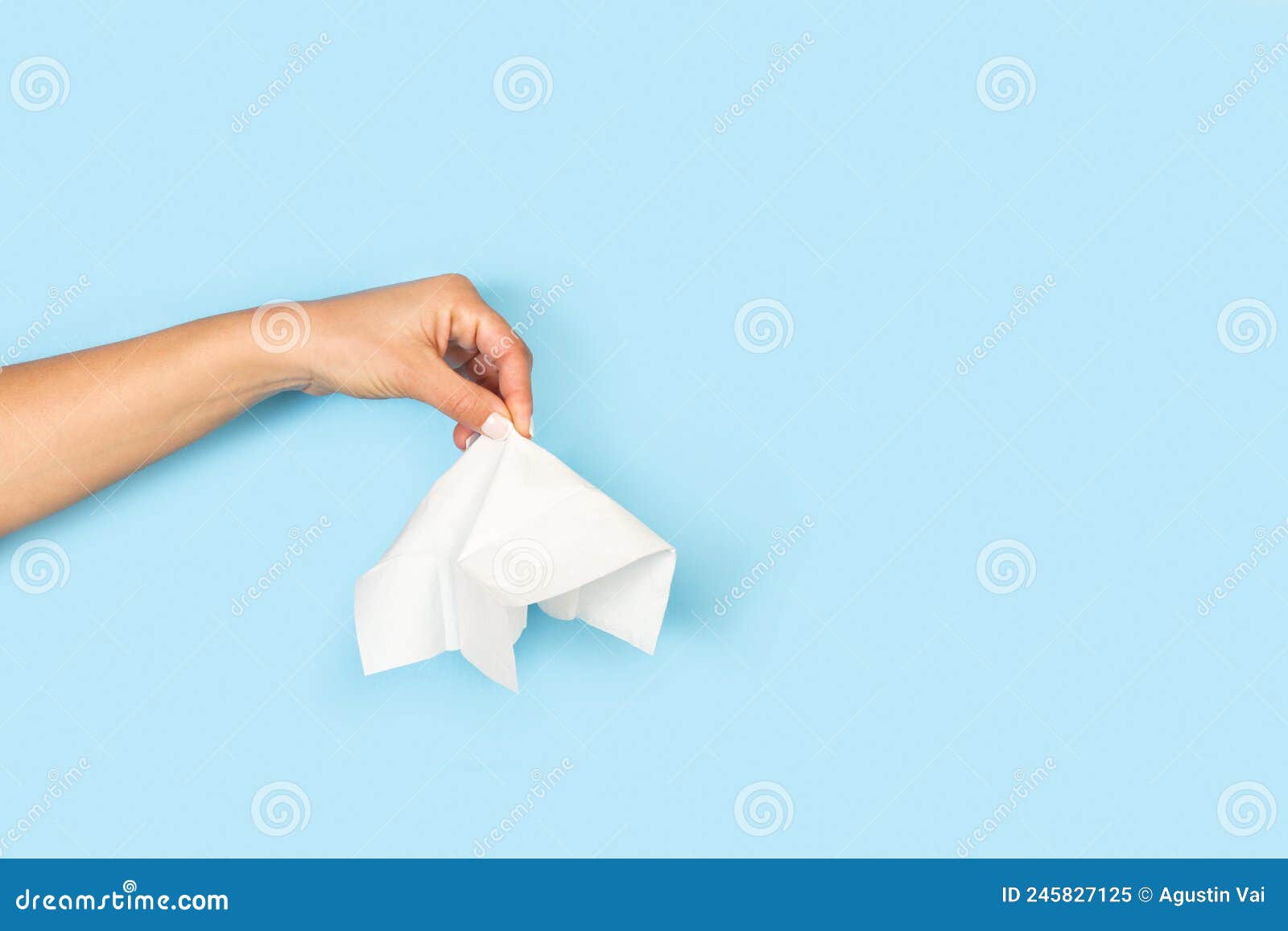 Woman Hand Holding a Tissue on a Light Blue Background Stock Image