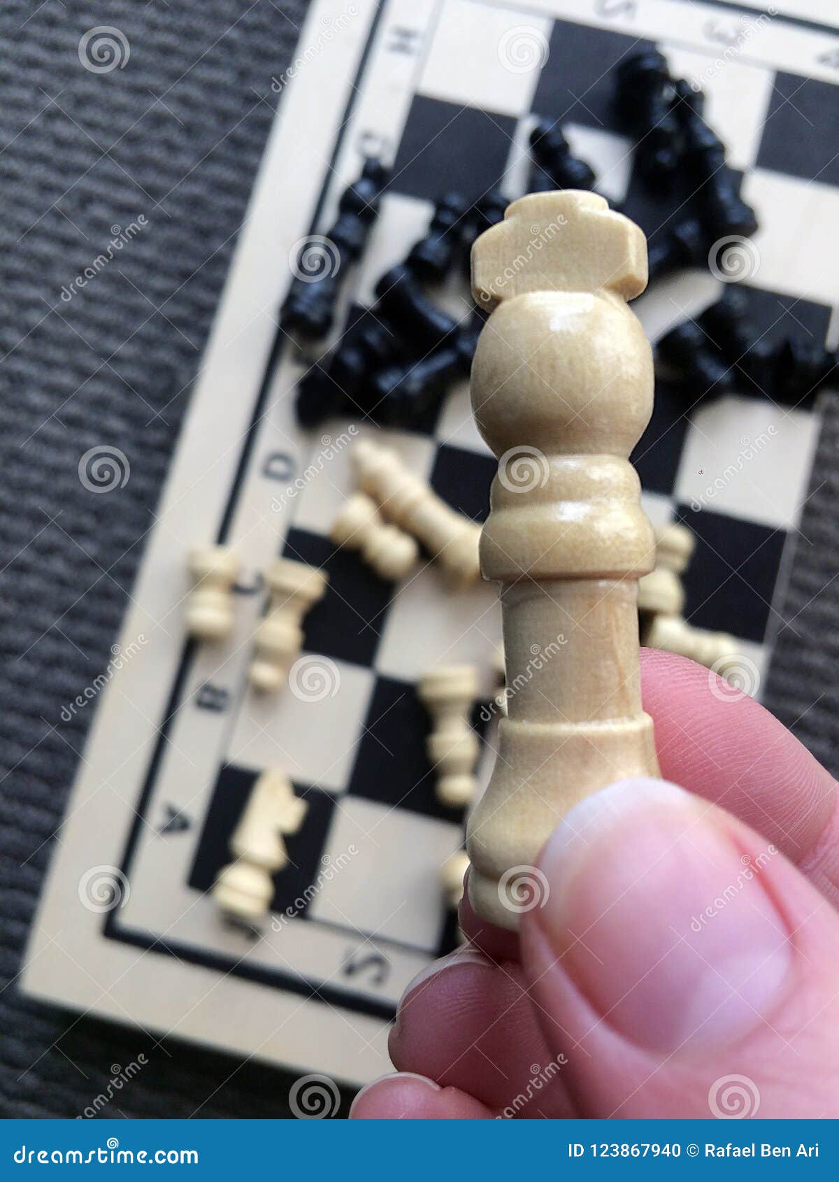 Woman Hand Holding a White Queen Piece Over a Chess Board