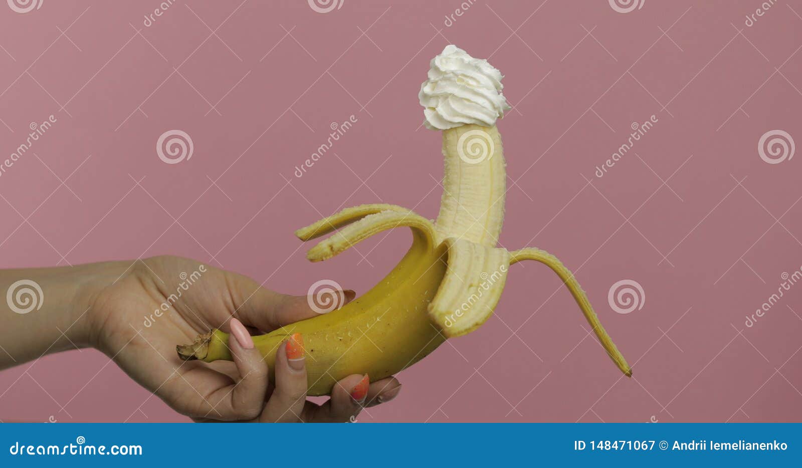 Woman Hand Holds Banana with Whipped Cream on Top of the Fruit