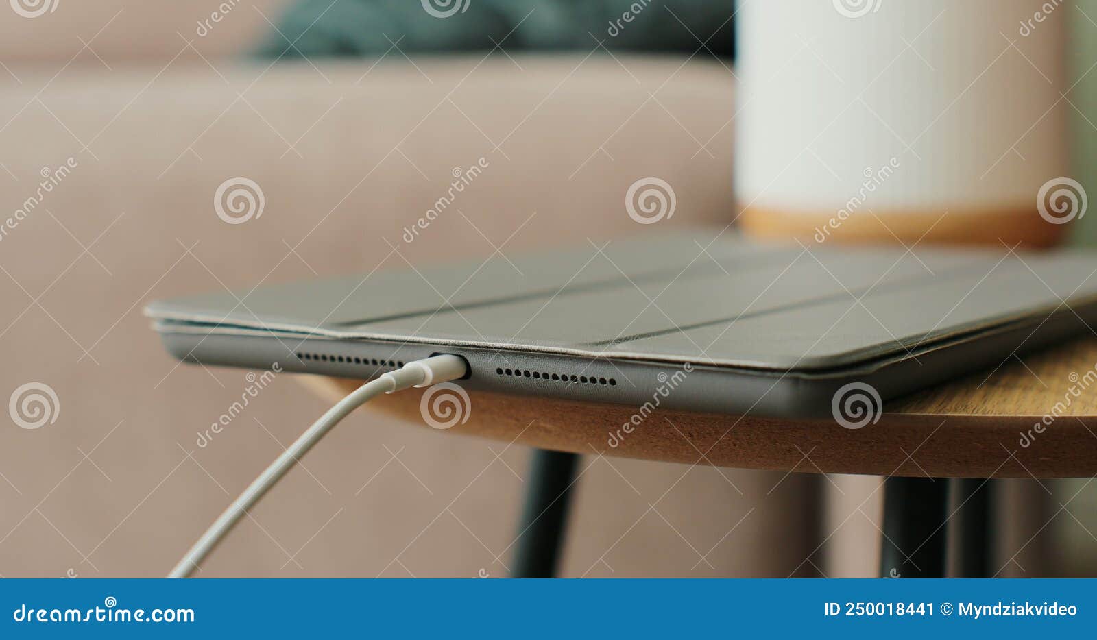 woman hand inserts the cable to charge the tabletpc on the table. close-up.