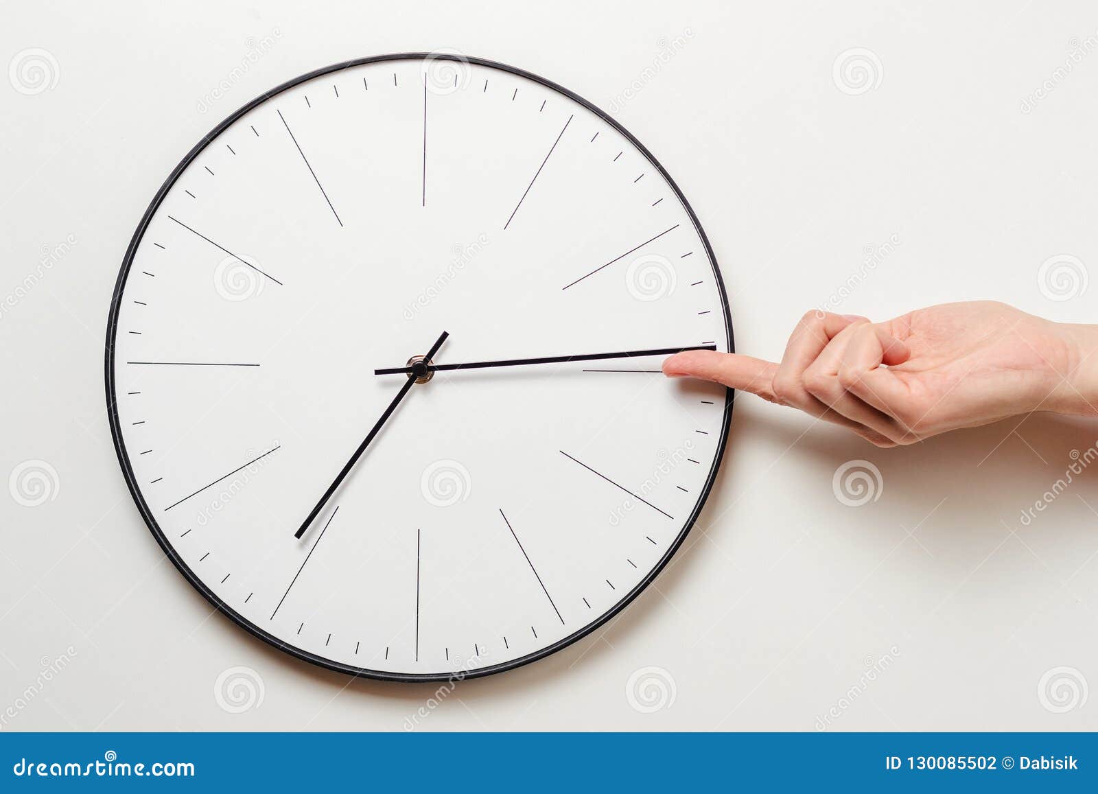 Woman hand stop time on round clock, female finger takes the minute arrow of the clock back, time management and deadline concept