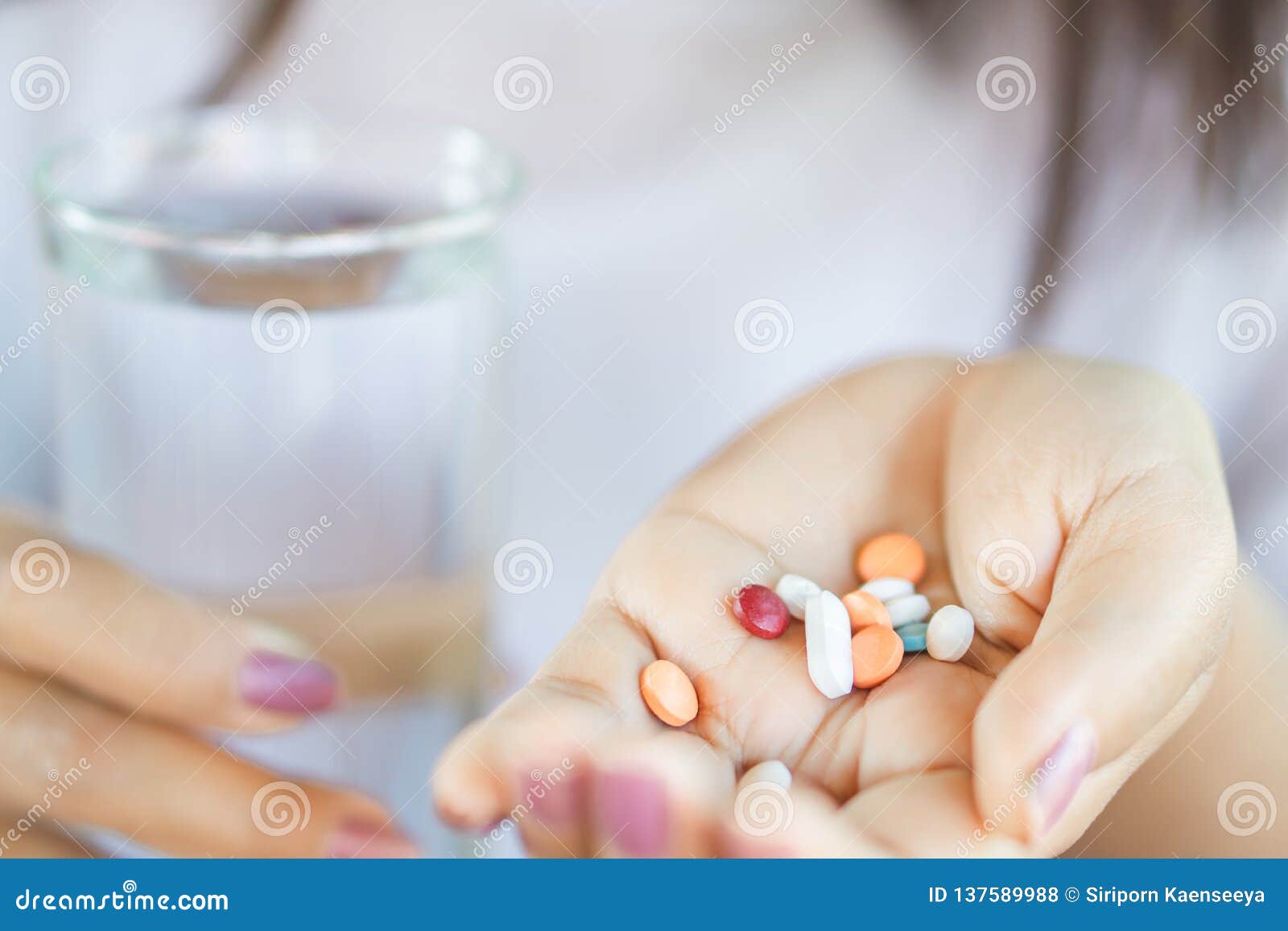 woman hand taking vitamins another hand holding glass of water
