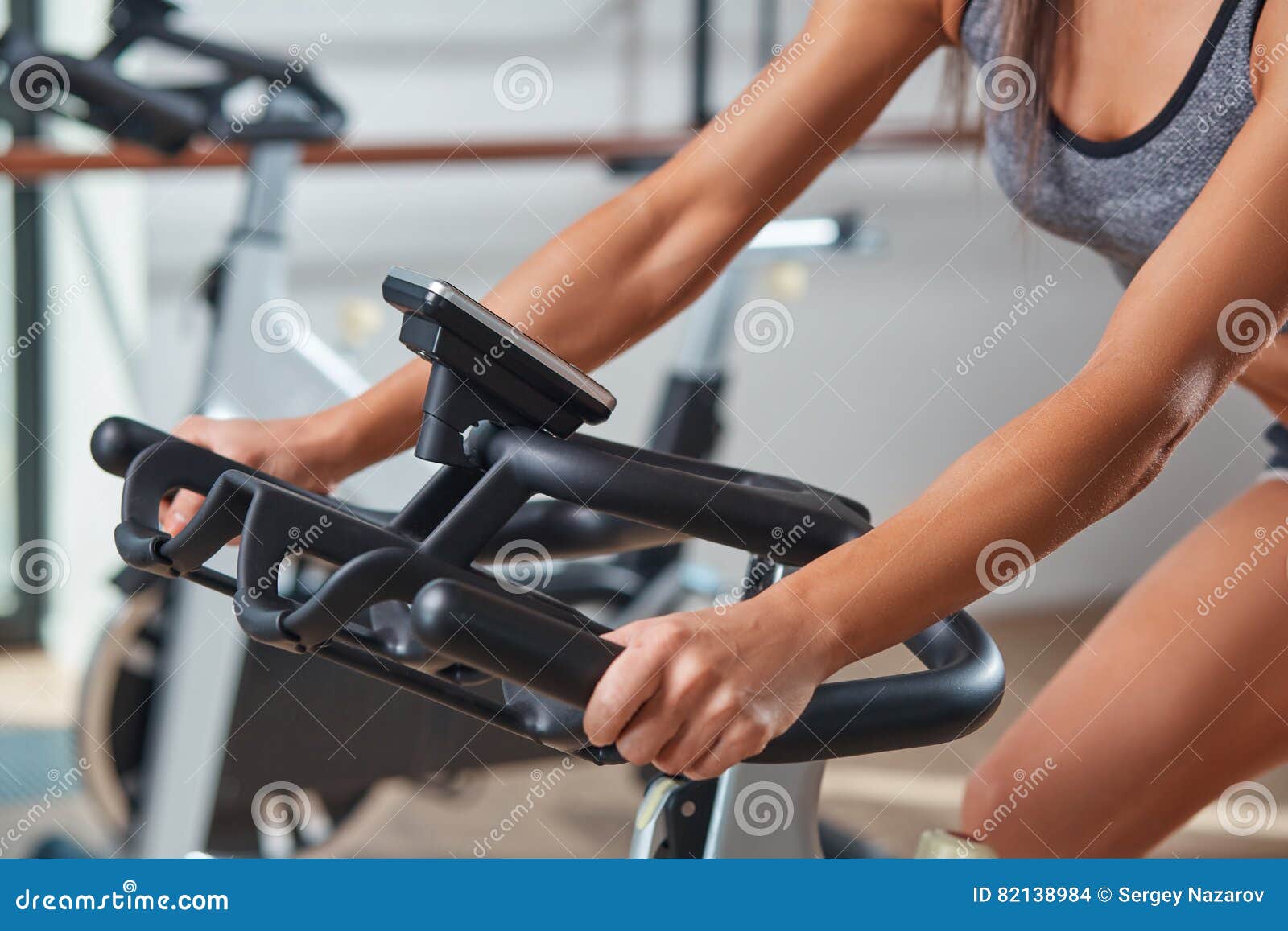 woman hands on a bar stationary bike the gym