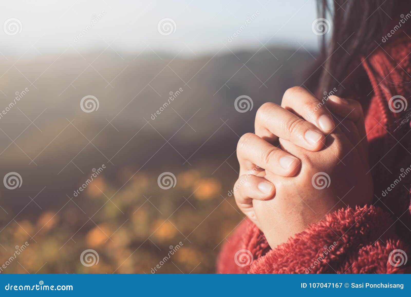woman hands folded in prayer in beautiful nature background