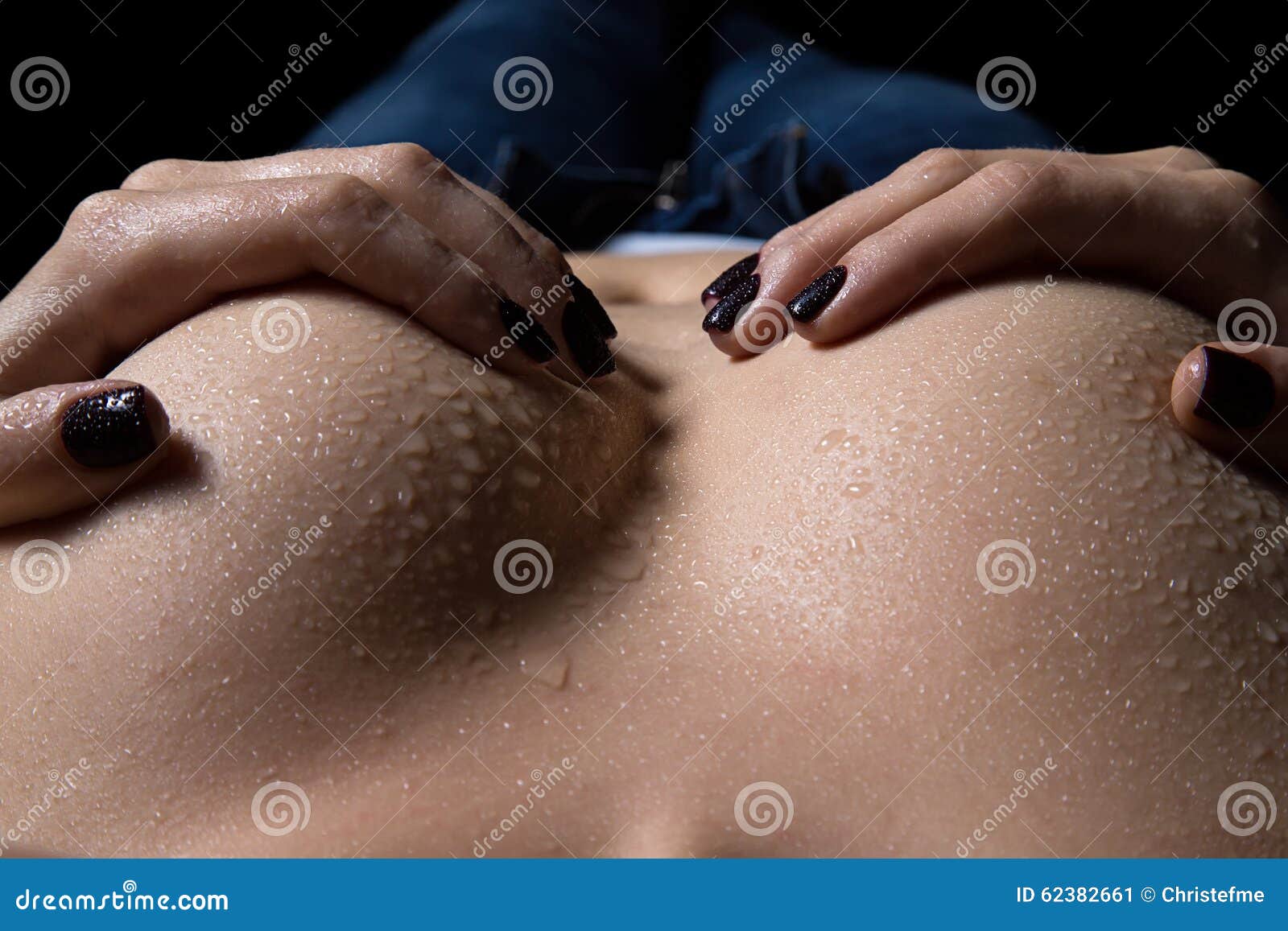 Woman Hands Holding Breasts with Drops in the Dark Stock Image