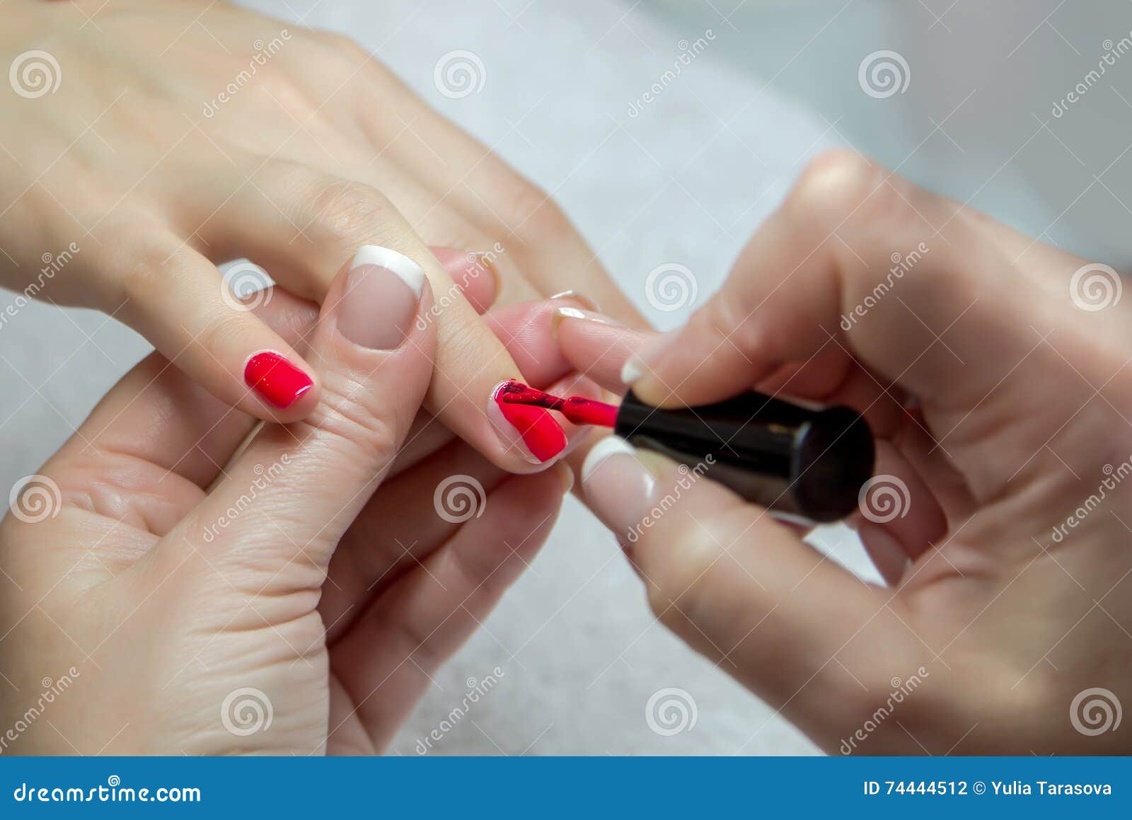 Woman receiving toenail pedicure service by pedicurist at nail salon.  Beautician coating red gel color toenail to customer at nail and spa salon.  Foot care and toenail treatment at nail salon. 7773681