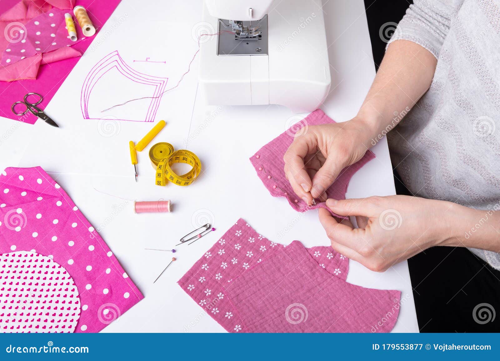 woman hands sewing a pink ladies face mask during the coronavirus pandemia.