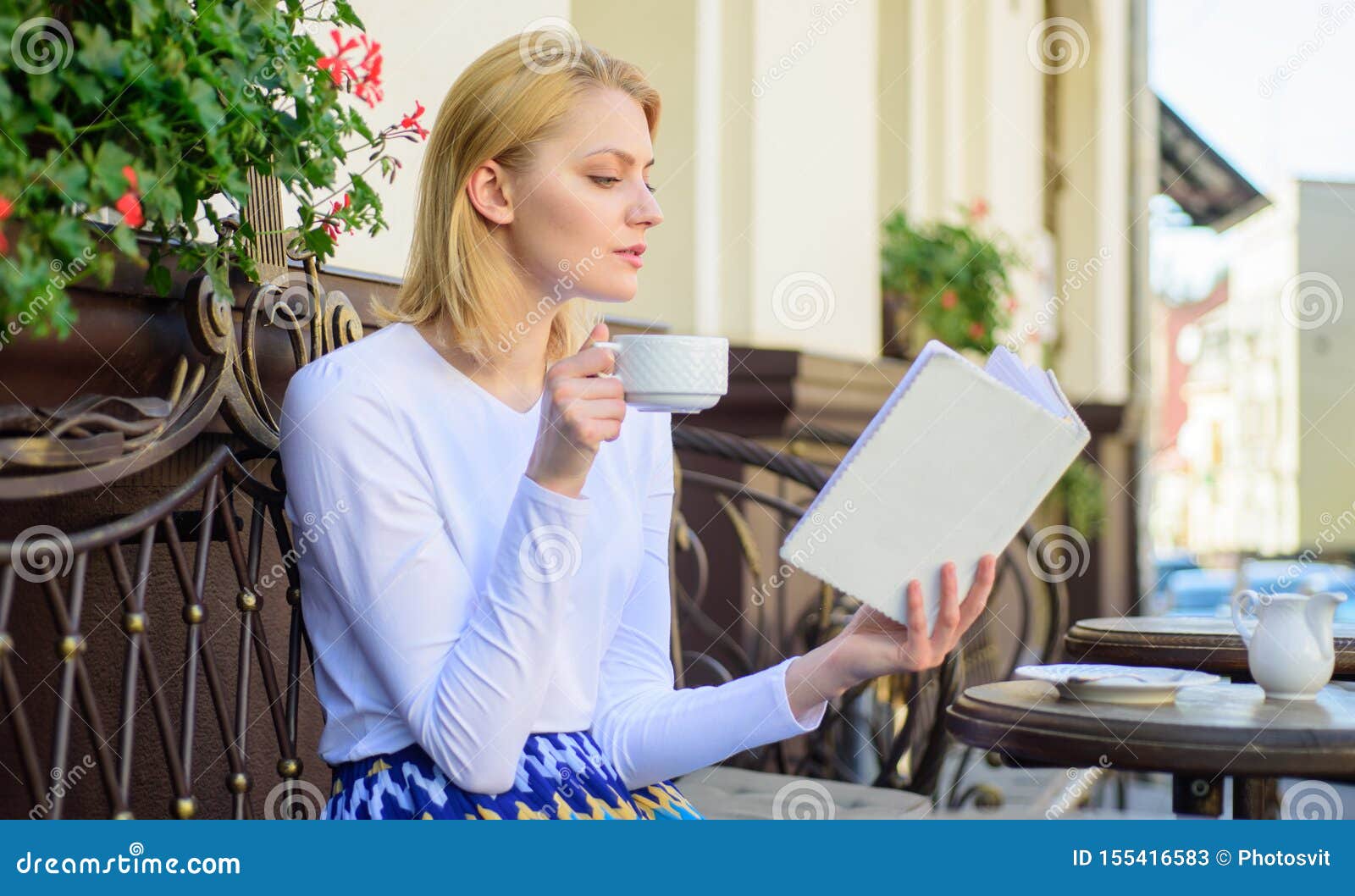 Woman have drink cafe terrace outdoors. Perfect morning concept. Girl drink coffee while read new bestseller book by popular author. Mug coffee and interesting book best combination perfect weekend.