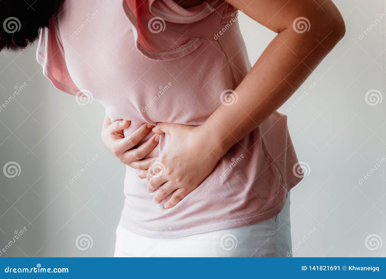 woman is having stomach ache or menstrual period, close-up portrait of young woman is suffering from abdominal pain at her home.