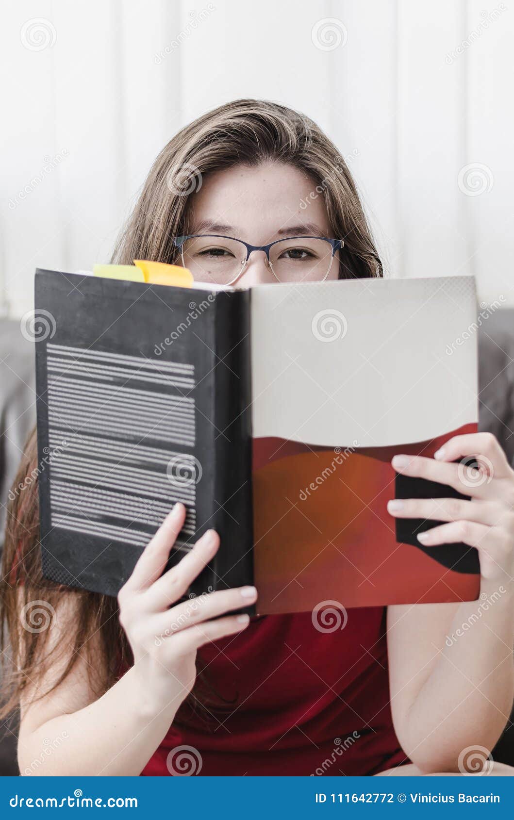 woman holding a book in front of her with just the eyes out of t