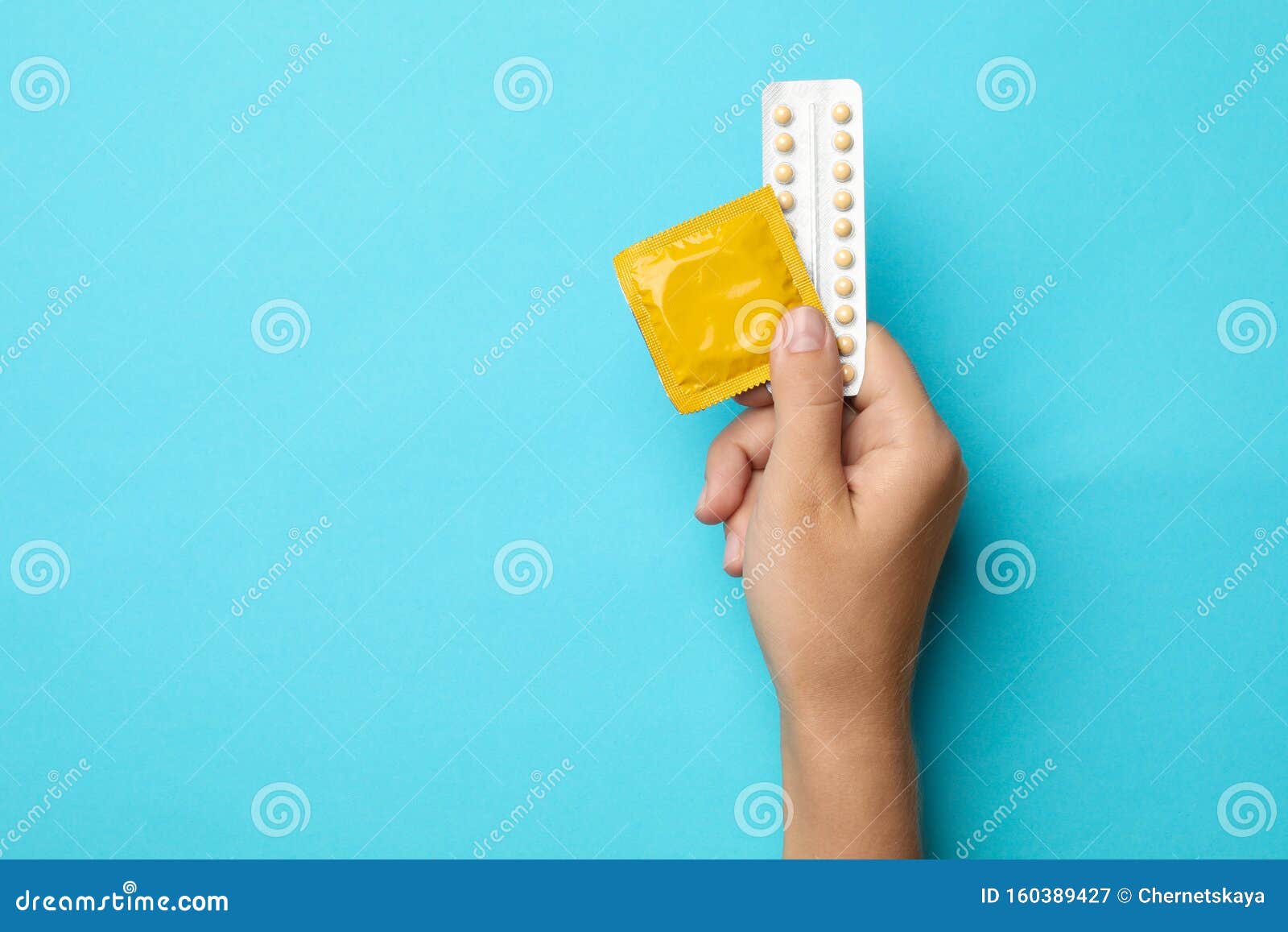 Woman Holding Condom And Birth Control Pills On Background Top View With Space For Text Safe 