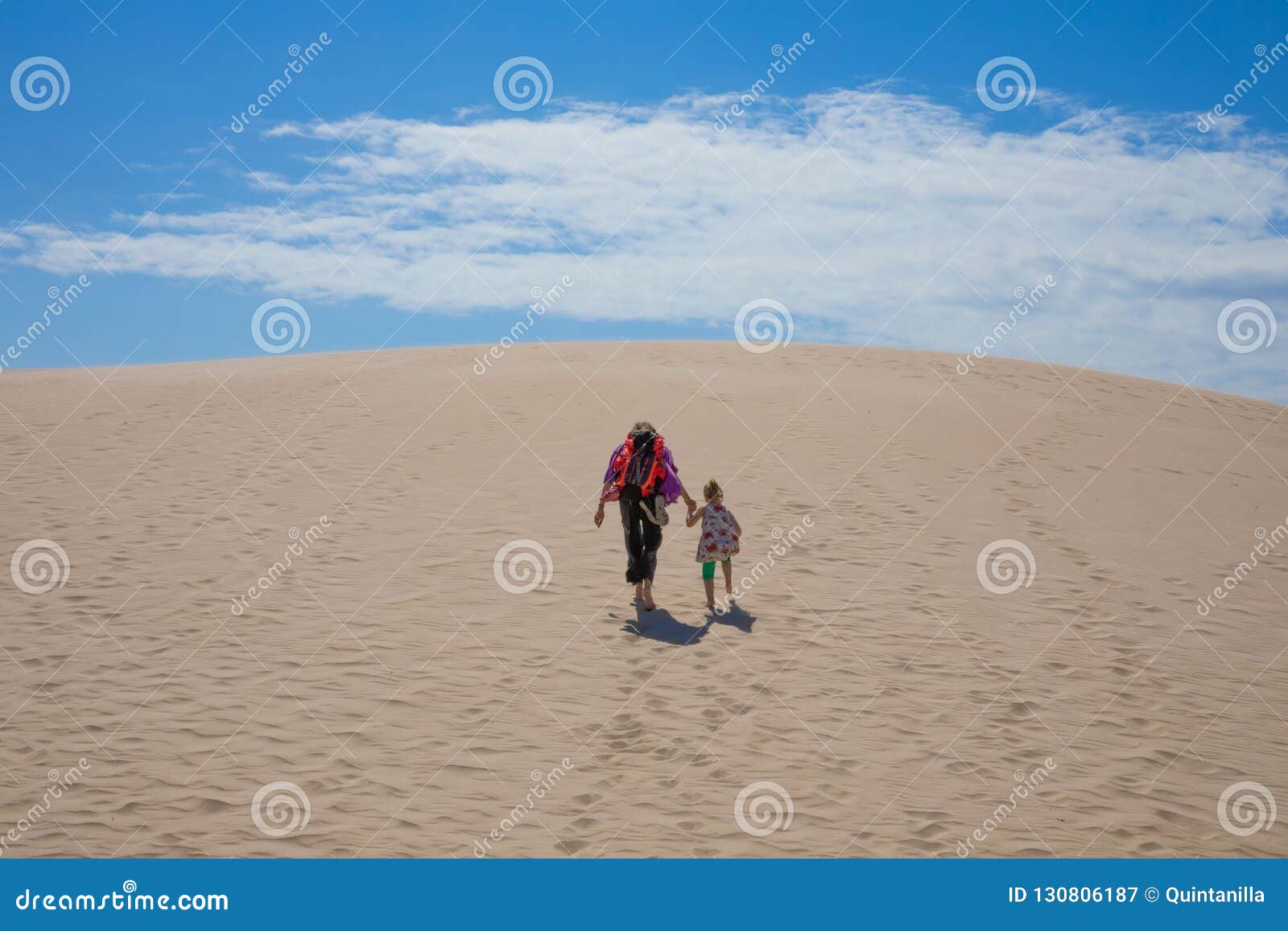 woman holding girl hand walking up the dune of bolonia beach in