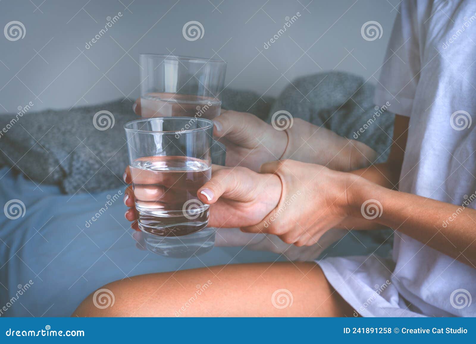 woman holding glass of water in shaky hands and suffering from parkinson& x27;s disease symptoms or essential tremor.