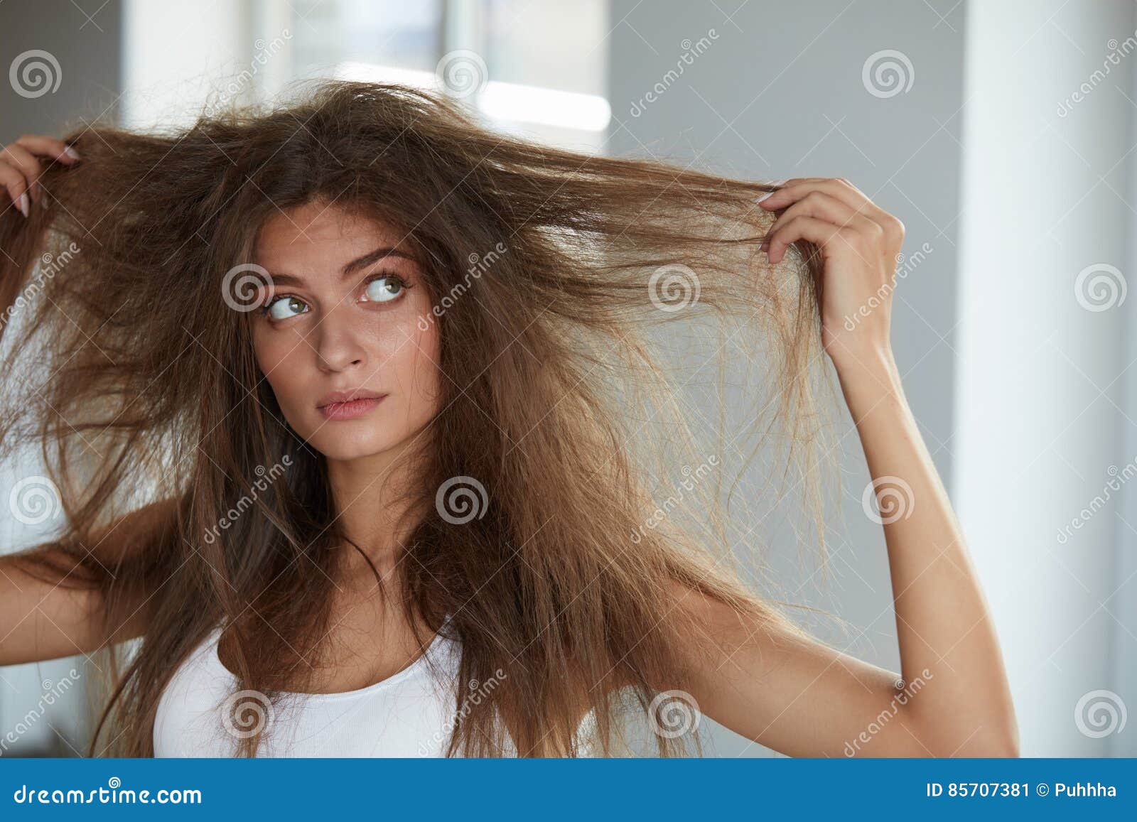 woman with holding long damaged dry hair. hair damage, haircare.