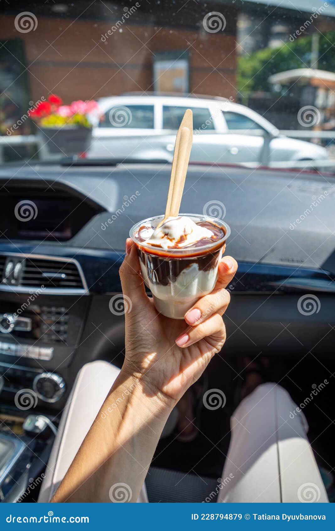woman holding the mcdonalds mcflurry ice cream with chocolate in a car after drive thru. drive thru concept