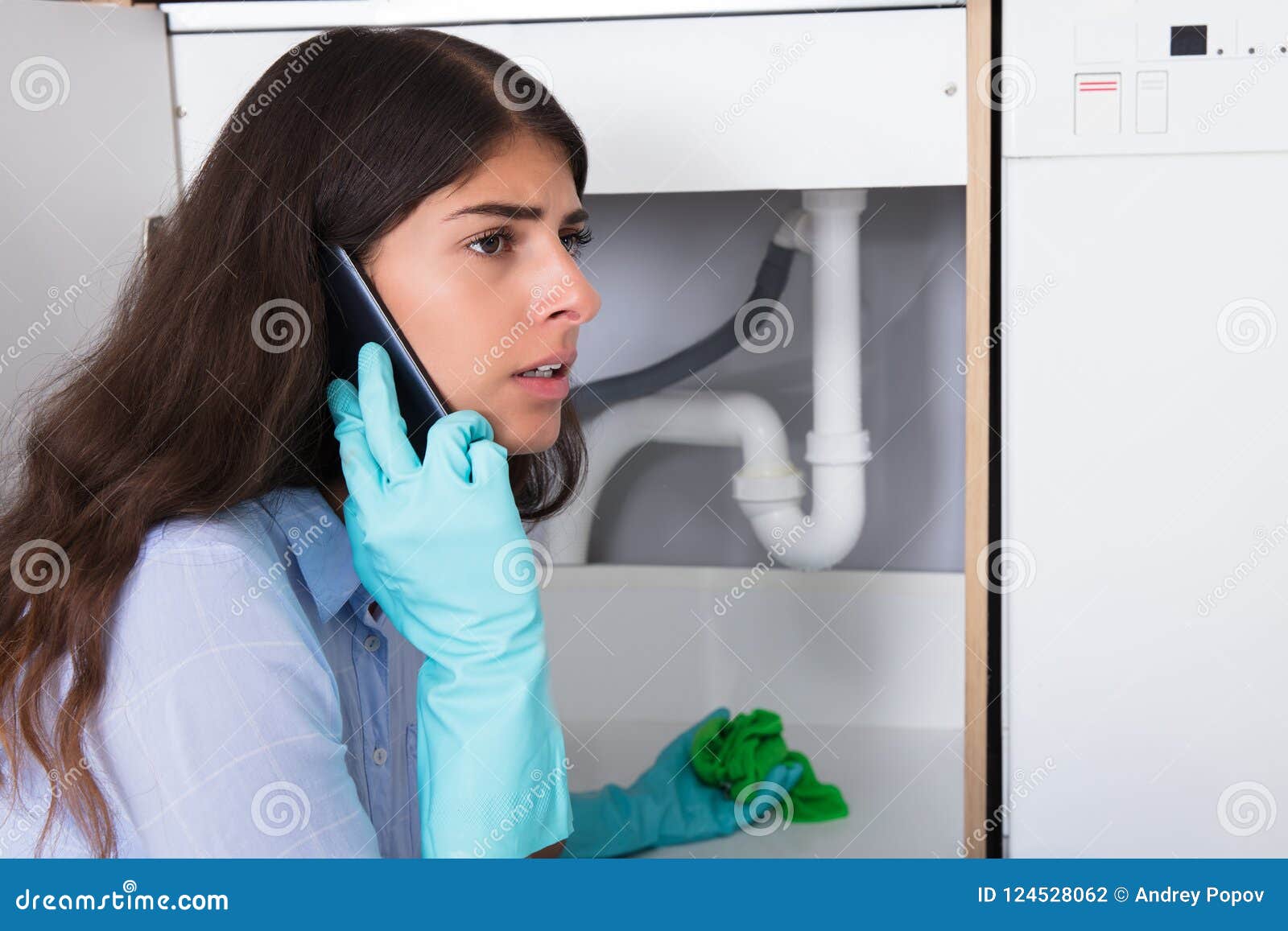 woman holding napkin under sink pipe leakage calling plumber