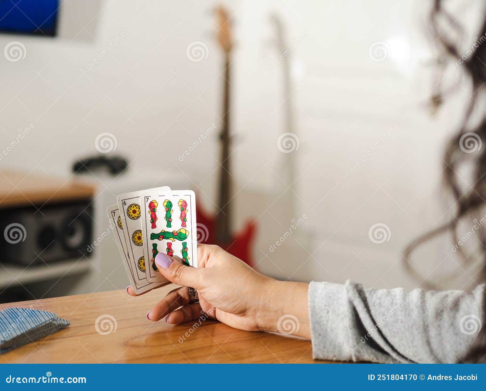 woman holding three cards for truco, a popular argentinian card game