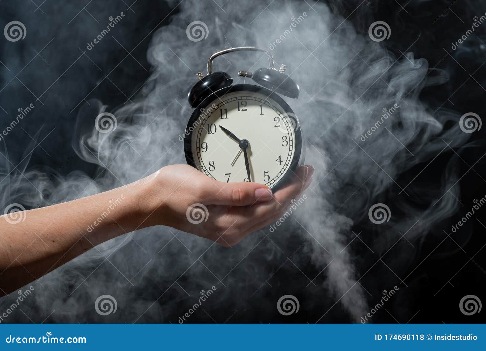 a woman holds an alarm clock in a studio full of smoke. white fog enveloped a round retro mechanical watch.